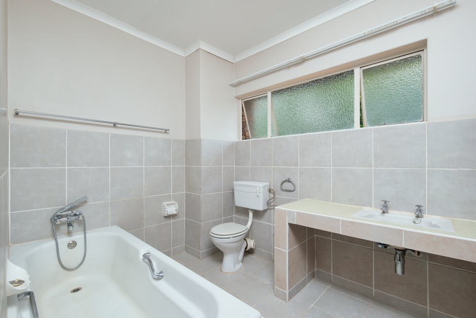 Spacious modern bathroom with clean tiled surfaces and natural light.